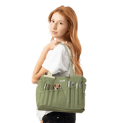 Woman holding a green painters bag with various tools in the pockets. 