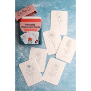 Set of flower paintable watercolor cards with a Cate Paper Co. packaging on a blue textured background.