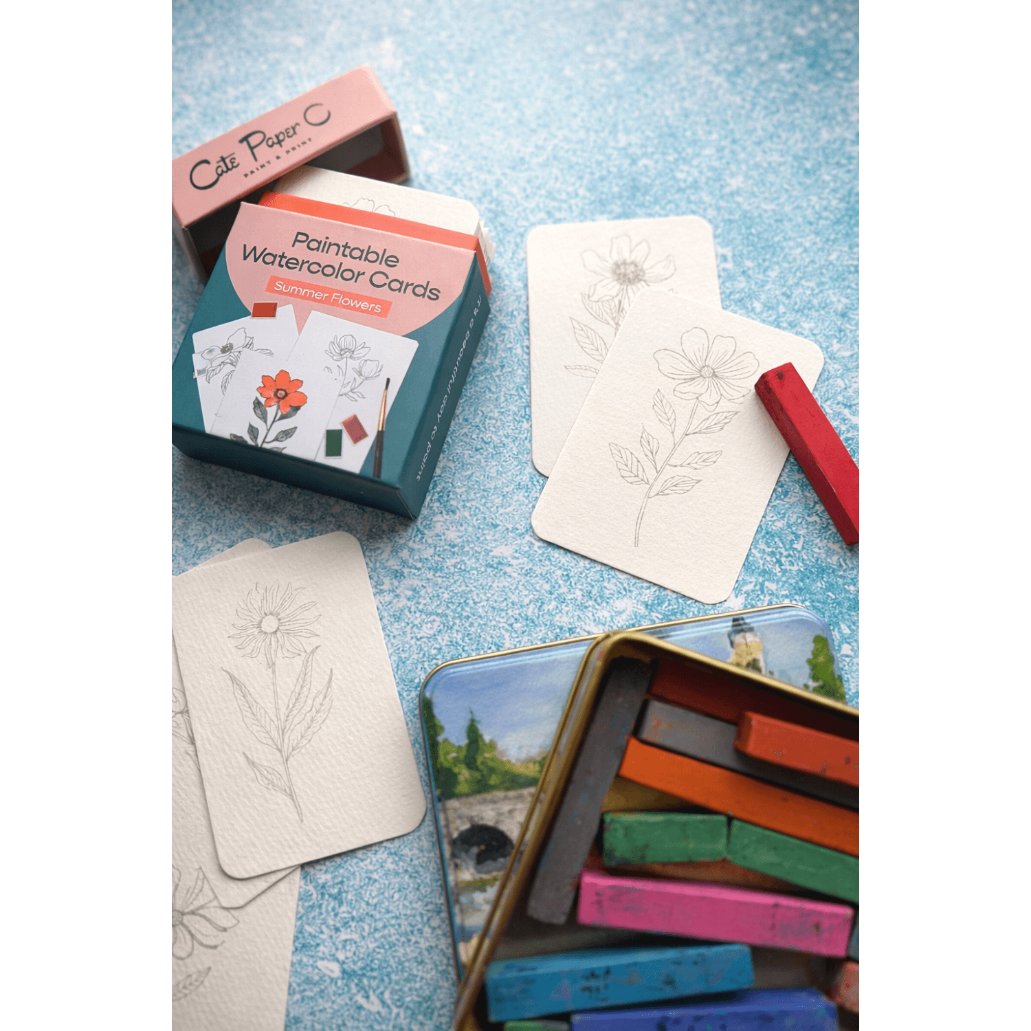 Paintable flower watercolor cards with a box and paint blocks on a textured surface