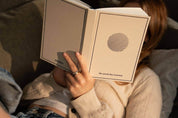 Person holding 'The Good Day Journal' book with a circular design on the cover.