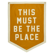Mustard banner with white text 'THIS MUST BE THE PLACE'