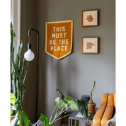 Decorative sign on a wall with plants and a lamp in a room.