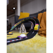 Toy car track set on a yellow carpet with toy cars on a blurred indoor background