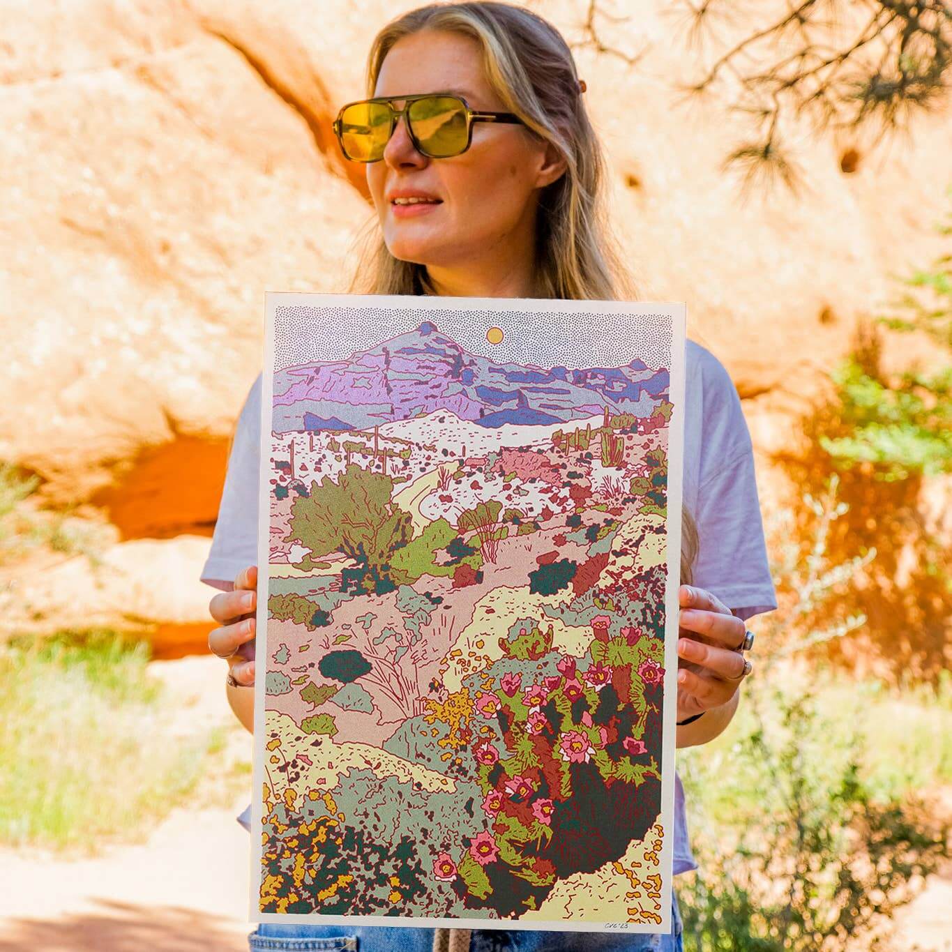 Woman holding a colorful landscape illustration outdoors